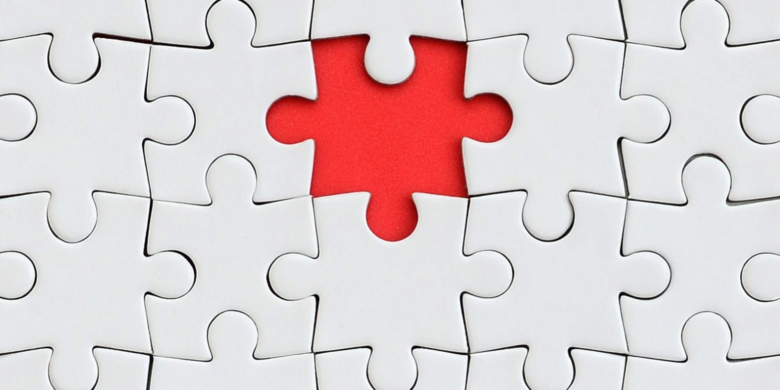 The texture of a white jigsaw puzzle in an assembled state with one missing element forming a red space
